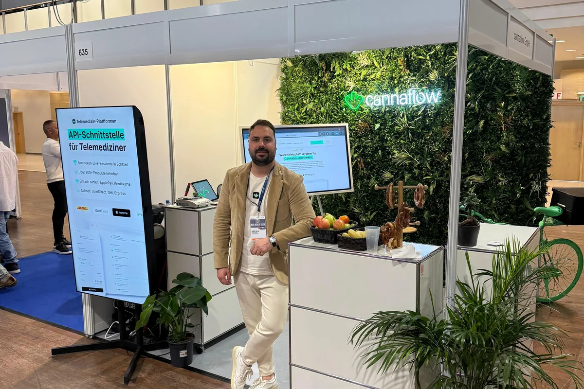 Henrik Willen am cannaflow-Messestand auf der ICBC Berlin: Pflanzenwand mit cannaflow-Logo, Display mit dem Warenwirtschaftssystem für Cannabis-Apotheken und Stele zur API-Schnittstelle für Telemediziner